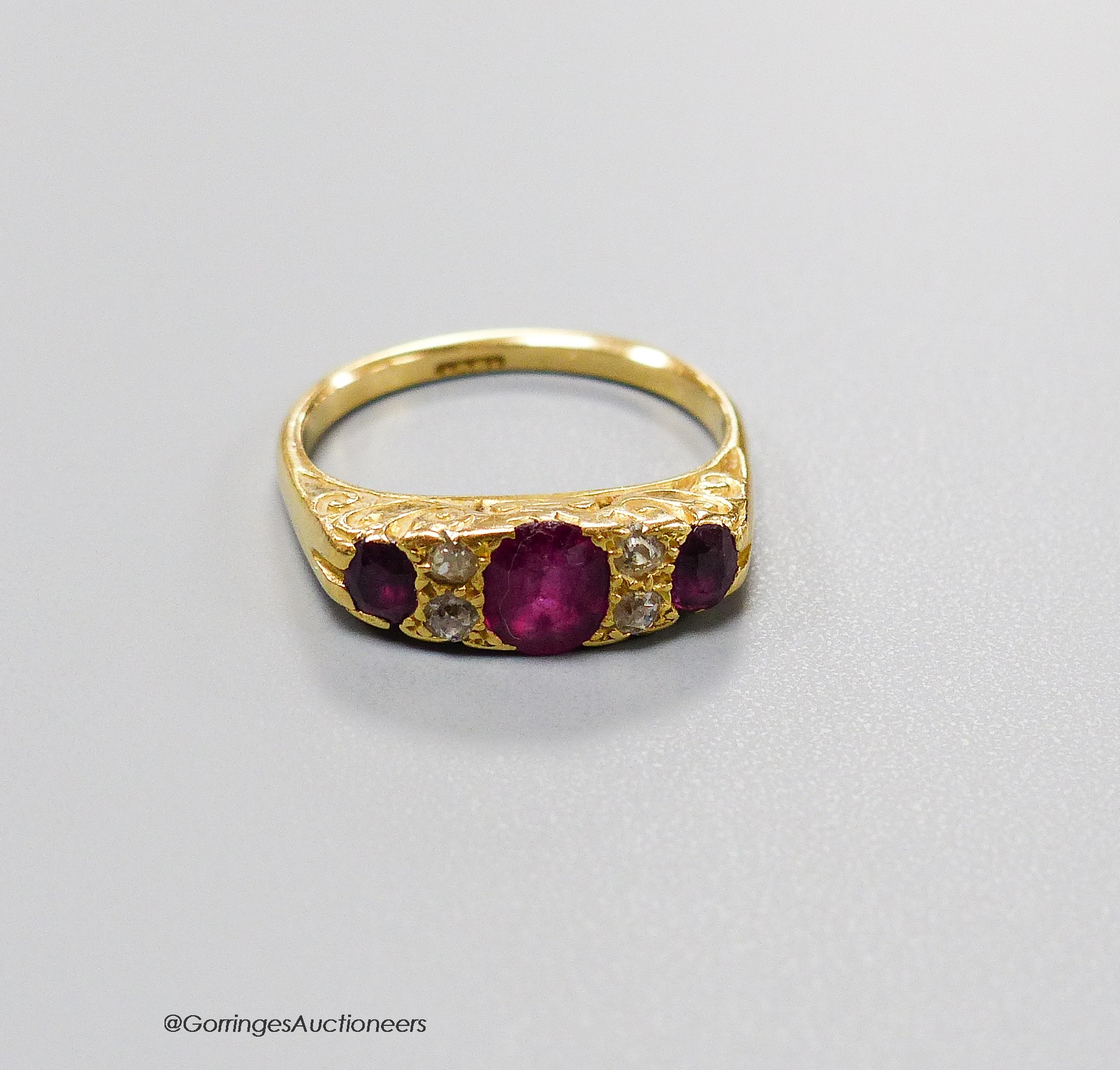 An early 20th century 18ct, three stone ruby and four stone diamond chip set half hoop ring, size L, gross 4.1 grams.
